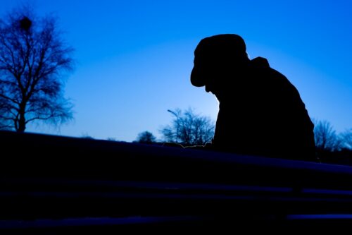 A man sits in a dark wintery landscape.