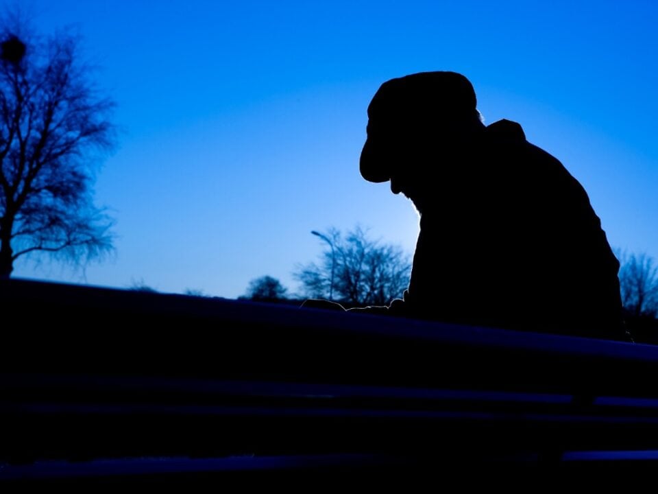 A man sits in a dark wintery landscape.
